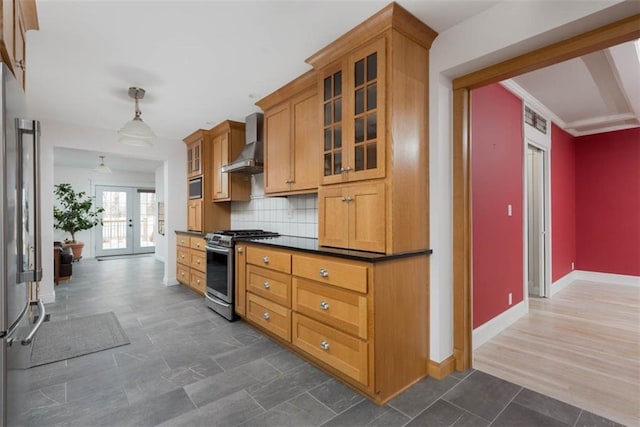 kitchen with wall chimney exhaust hood, glass insert cabinets, appliances with stainless steel finishes, french doors, and backsplash