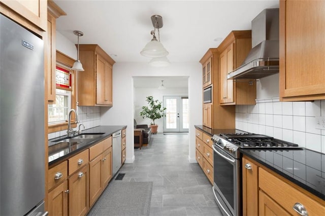 kitchen with french doors, stainless steel appliances, decorative backsplash, a sink, and wall chimney range hood