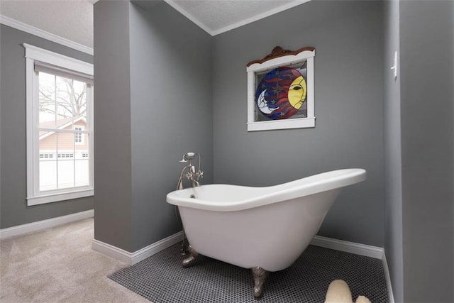 full bathroom with a textured ceiling, crown molding, a freestanding tub, and baseboards