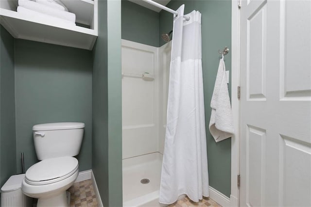 bathroom featuring a stall shower, baseboards, and toilet