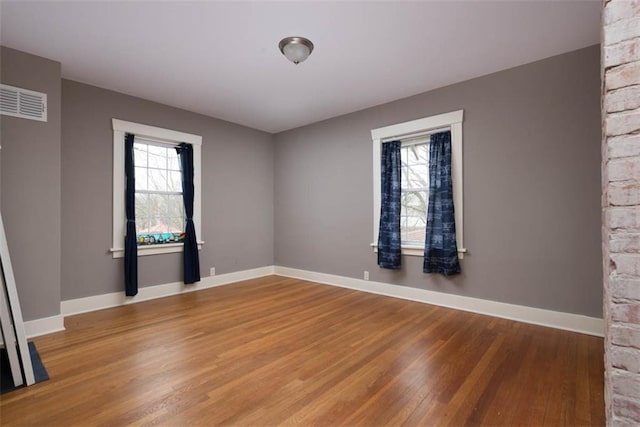 unfurnished room with light wood-type flooring, baseboards, visible vents, and a wealth of natural light