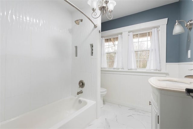 bathroom featuring marble finish floor, toilet, wainscoting, vanity, and  shower combination