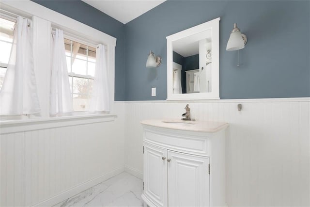 bathroom featuring marble finish floor, a wainscoted wall, and vanity