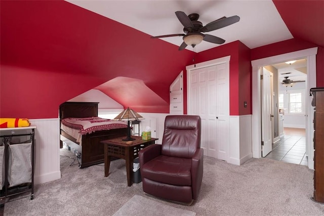 sitting room featuring carpet floors, lofted ceiling, a wainscoted wall, and a ceiling fan