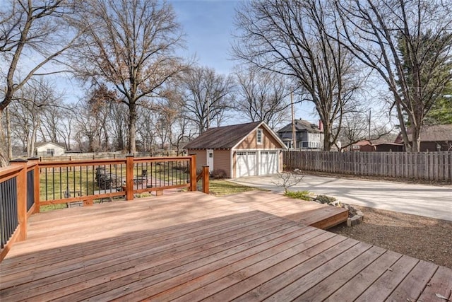 wooden terrace featuring a garage, an outdoor structure, and fence