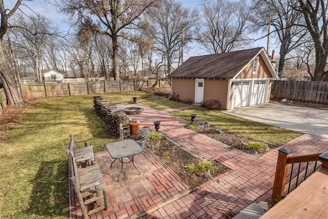 view of yard featuring an outbuilding, a detached garage, an outdoor fire pit, and fence private yard