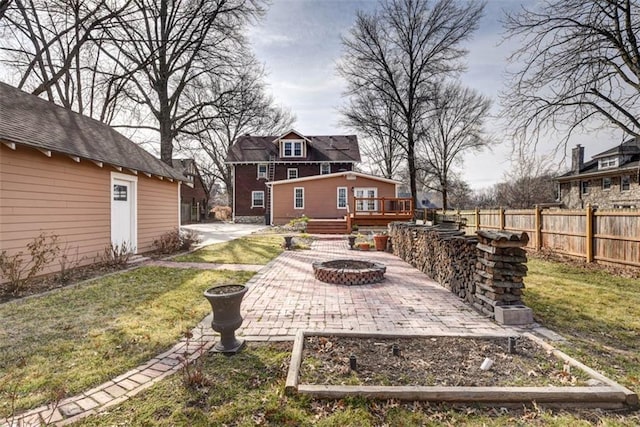 view of yard featuring fence, a fire pit, a patio, and a wooden deck