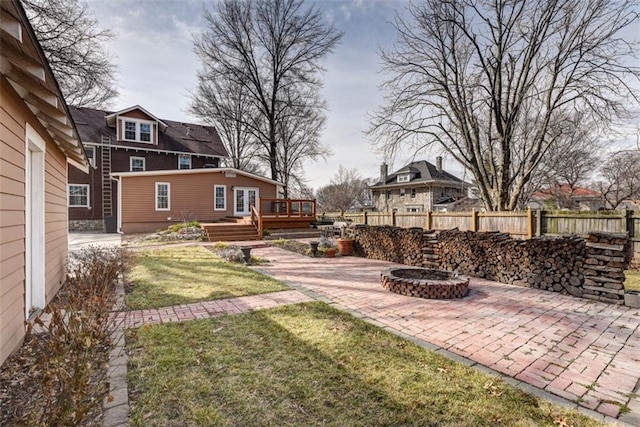 view of yard with a deck, fence, a fire pit, and a patio