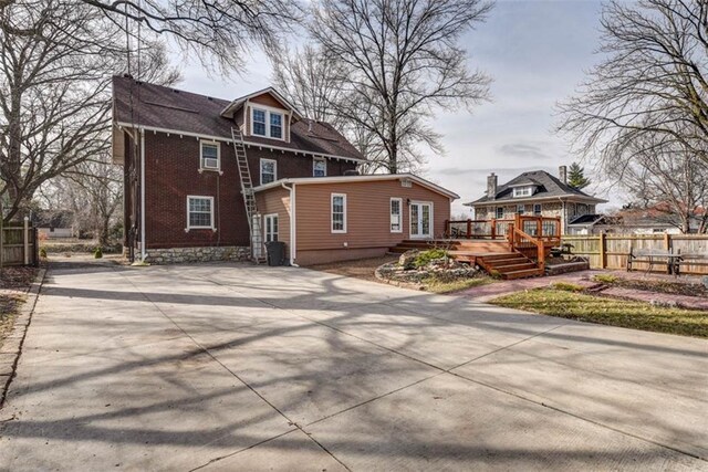 exterior space with brick siding, fence, and a wooden deck