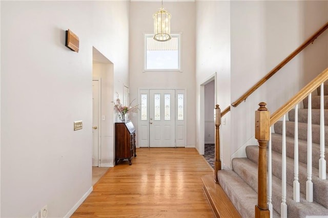 entrance foyer with an inviting chandelier, light wood-style flooring, stairway, and a high ceiling