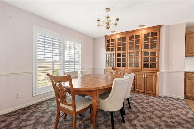 dining space with dark colored carpet, baseboards, and a chandelier