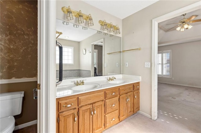 bathroom with double vanity, toilet, a ceiling fan, and a sink