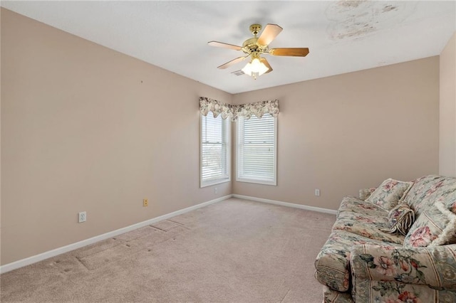 unfurnished room featuring light colored carpet, a ceiling fan, and baseboards