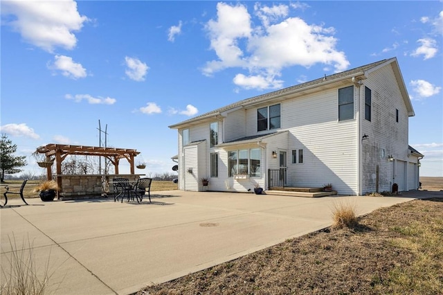 rear view of house featuring a garage, a patio area, a pergola, and driveway