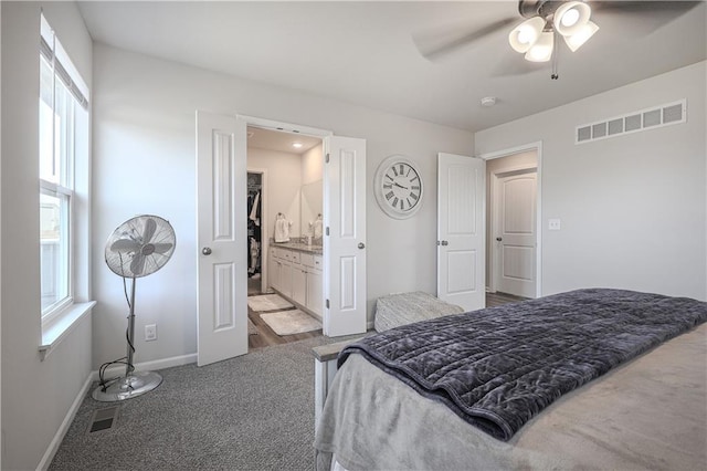 bedroom with baseboards, visible vents, carpet floors, and connected bathroom