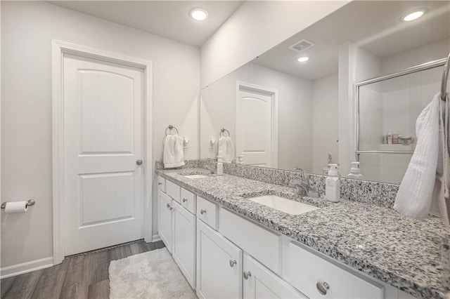 full bath with double vanity, visible vents, wood finished floors, and a sink