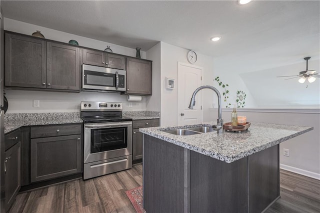 kitchen featuring a sink, light stone counters, dark wood finished floors, dark brown cabinetry, and appliances with stainless steel finishes