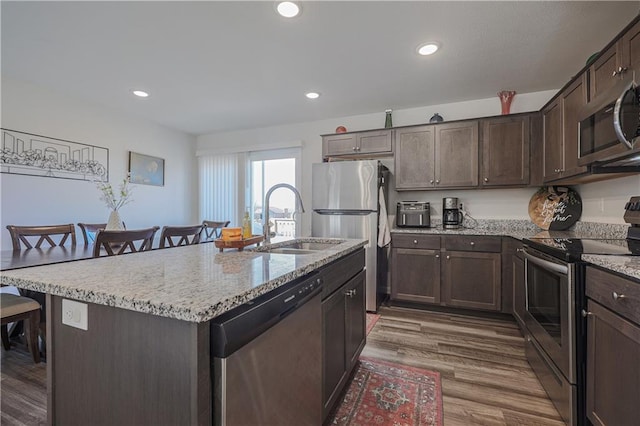 kitchen featuring a sink, dark brown cabinetry, a breakfast bar area, and stainless steel appliances