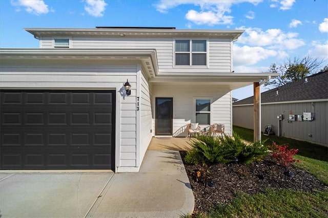 view of front of property featuring a porch, concrete driveway, and a garage