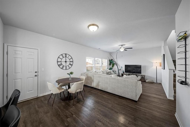 living room with ceiling fan, a textured ceiling, baseboards, and wood finished floors