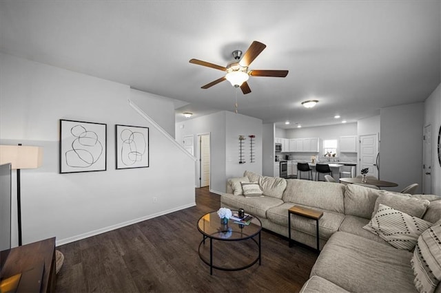 living area with ceiling fan, dark wood finished floors, and baseboards