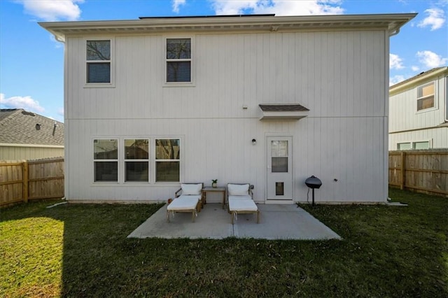 back of property with a fenced backyard, a lawn, and a patio