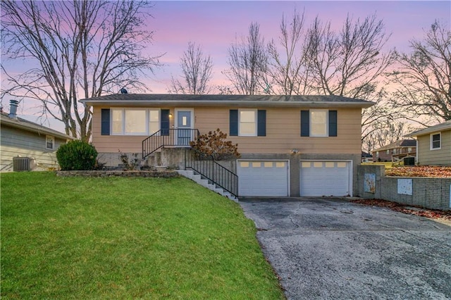 view of front of property featuring driveway, a front lawn, central AC, and an attached garage