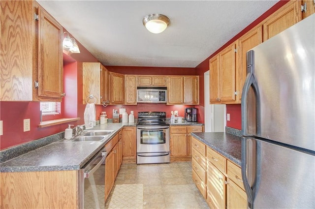 kitchen featuring stainless steel appliances, dark countertops, and a sink