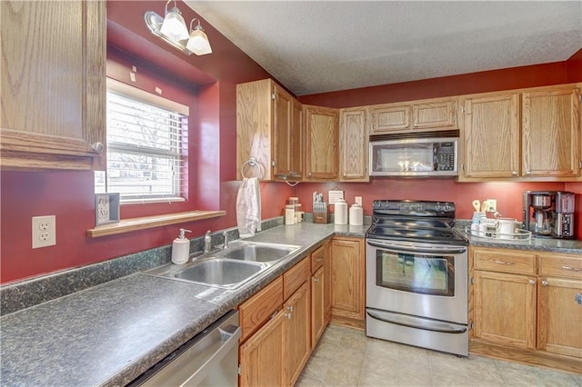 kitchen featuring a textured ceiling, stainless steel appliances, dark countertops, and a sink