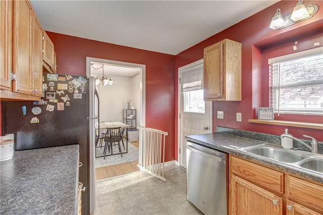 kitchen with appliances with stainless steel finishes, dark countertops, a healthy amount of sunlight, and a sink