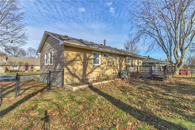 back of property featuring a gate, fence, a lawn, and a wooden deck