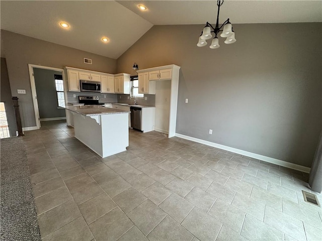 kitchen featuring a center island, stainless steel appliances, visible vents, white cabinets, and a sink