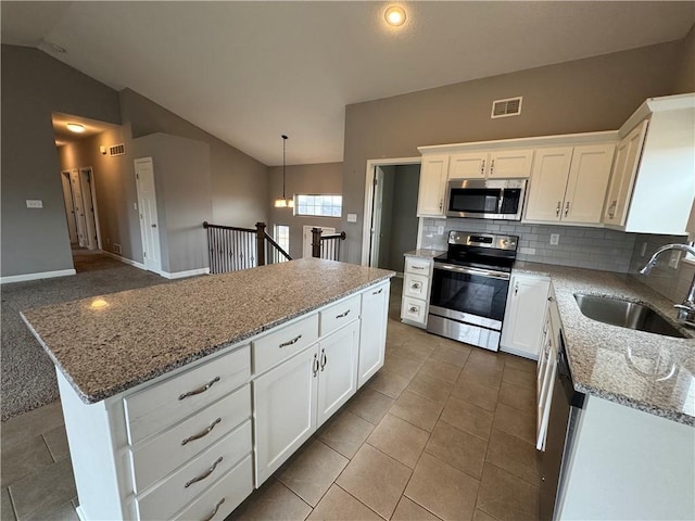 kitchen with lofted ceiling, visible vents, appliances with stainless steel finishes, white cabinetry, and a sink