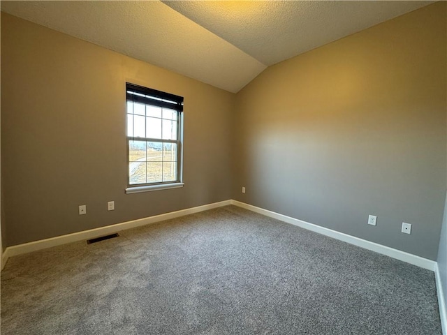 carpeted empty room featuring visible vents, baseboards, vaulted ceiling, and a textured ceiling