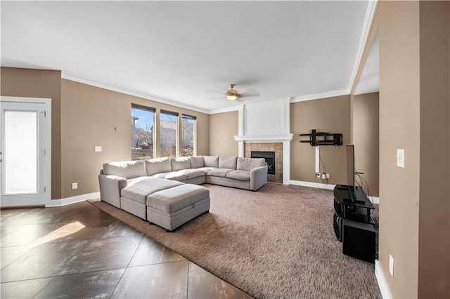 living area featuring baseboards, ceiling fan, a tile fireplace, and ornamental molding