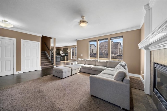 carpeted living room with baseboards, a fireplace, stairs, tile patterned flooring, and crown molding