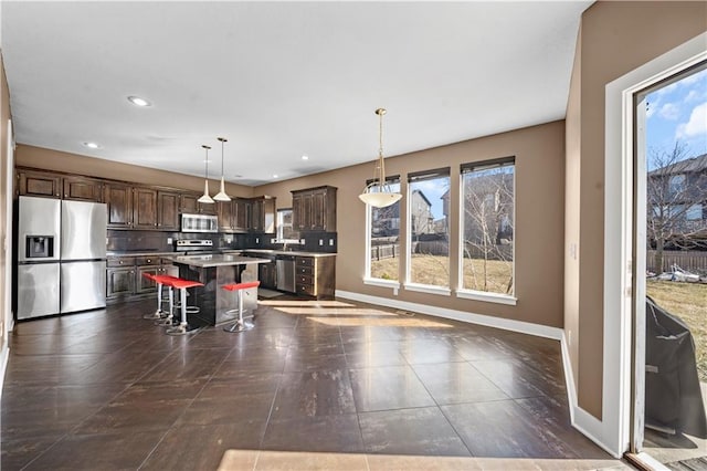 kitchen featuring stainless steel appliances, baseboards, a kitchen island, and a breakfast bar