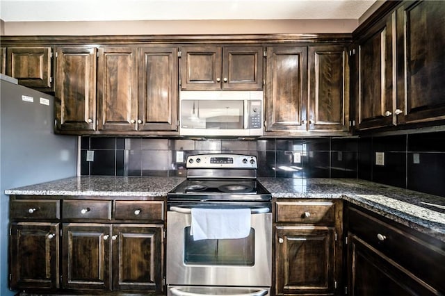 kitchen featuring stone counters, stainless steel appliances, backsplash, and dark brown cabinets