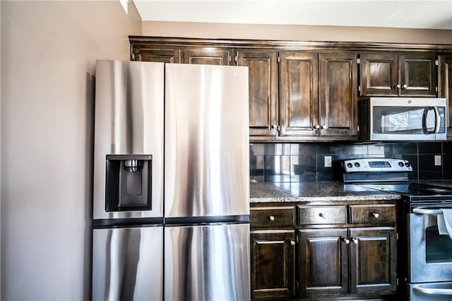 kitchen featuring stainless steel appliances, tasteful backsplash, dark brown cabinetry, and dark stone counters