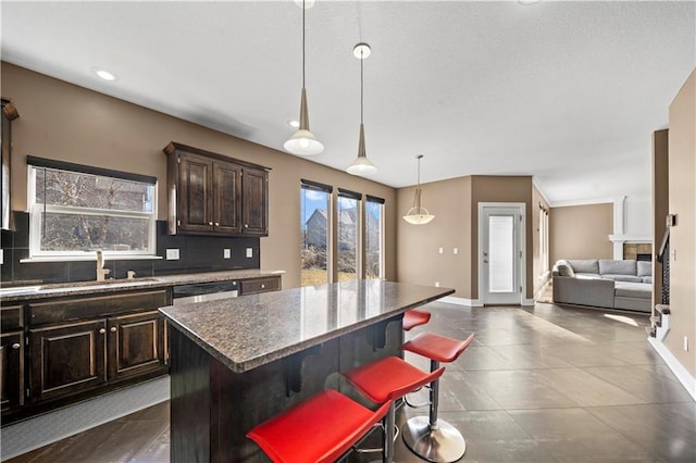 kitchen featuring a breakfast bar area, baseboards, a kitchen island, dark brown cabinetry, and backsplash