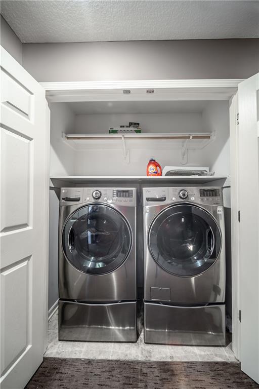 laundry room featuring laundry area, a textured ceiling, and separate washer and dryer