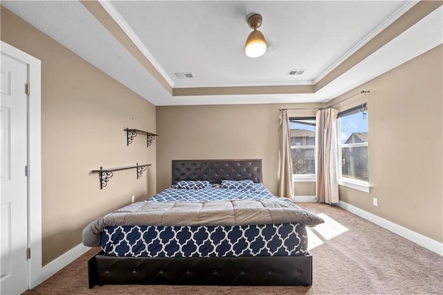 carpeted bedroom with a tray ceiling, baseboards, visible vents, and ornamental molding