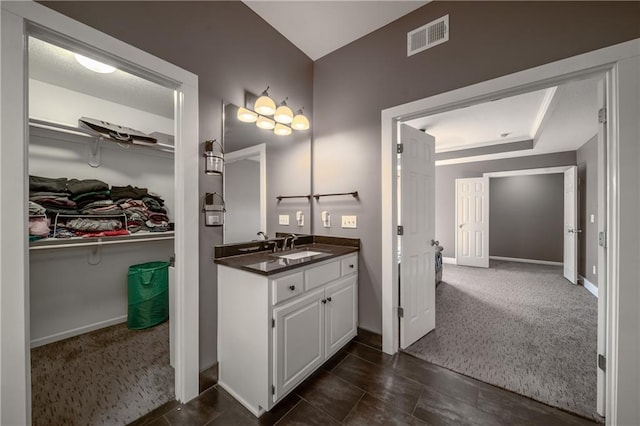 bathroom featuring visible vents, baseboards, a walk in closet, and vanity