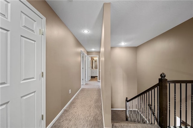 corridor with baseboards, an upstairs landing, carpet flooring, recessed lighting, and a textured ceiling