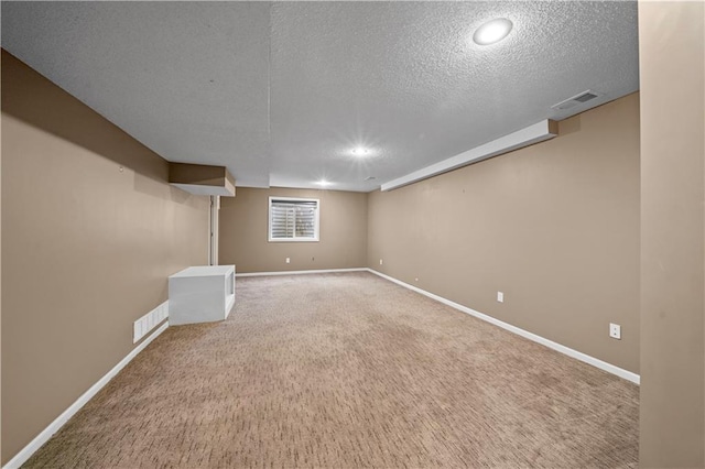 basement featuring baseboards, carpet, and a textured ceiling