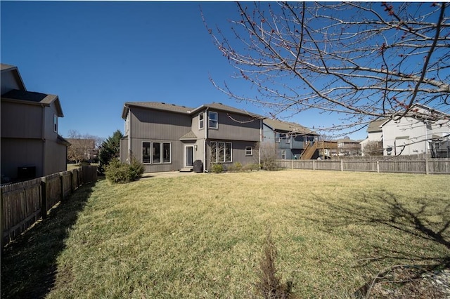 rear view of property with a yard and a fenced backyard