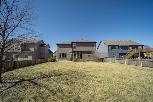 rear view of house featuring a residential view, a lawn, and a fenced backyard