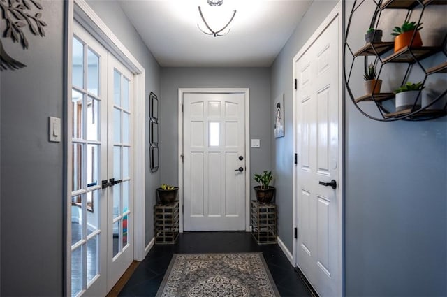 entryway with french doors, dark tile patterned floors, and baseboards