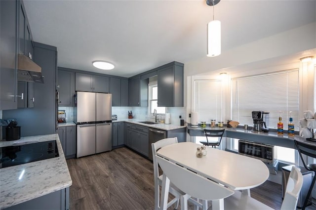 kitchen with dark wood-style floors, stainless steel appliances, decorative backsplash, a sink, and under cabinet range hood