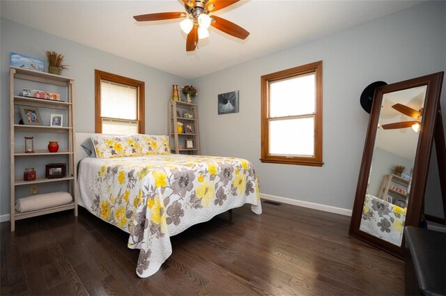 bedroom featuring dark wood-style floors, multiple windows, ceiling fan, and baseboards